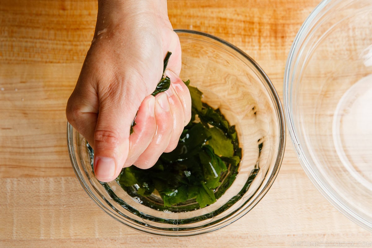 Squeeze water out from the rehydrated wakame seaweed.