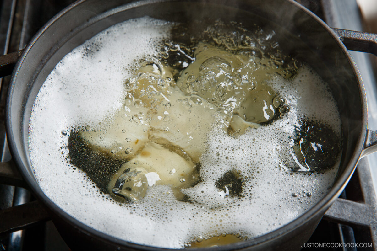 A close-up of pasta boiling in a pot of water on the stove, with bubbles and foam forming on the surface—perfect for pairing with Japanese potato salad.