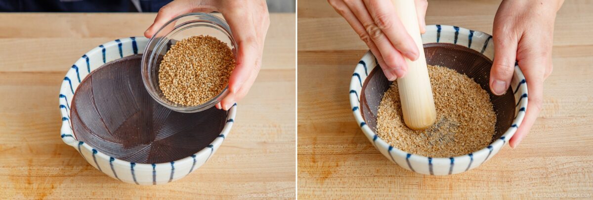 A hand pours sesame seeds into a striped ceramic bowl, then uses a wooden pestle to grind them—an essential step in preparing aromatic tan tan udon—on a wooden surface.